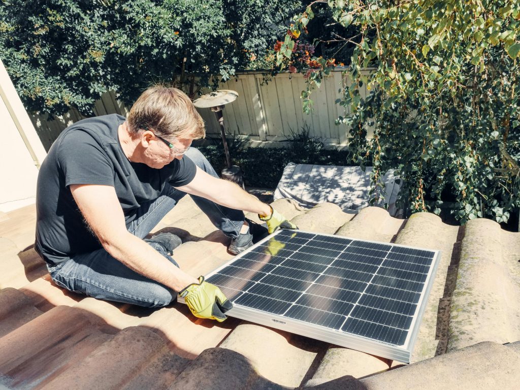 hombre instalando panel solar en tejado casa